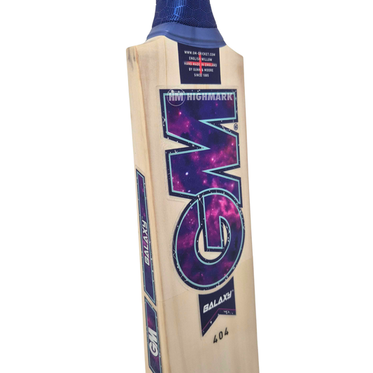 A close-up of a cricket bat showing the blade, featuring a large purple and blue galaxy-style 'GM' logo, a blue grip, and a white wood finish, on a plain white background.