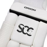 Close-up of a white sports protective pad with black branding, showing the word ORION on the upper section and a stylized SCC logo on the central pad.